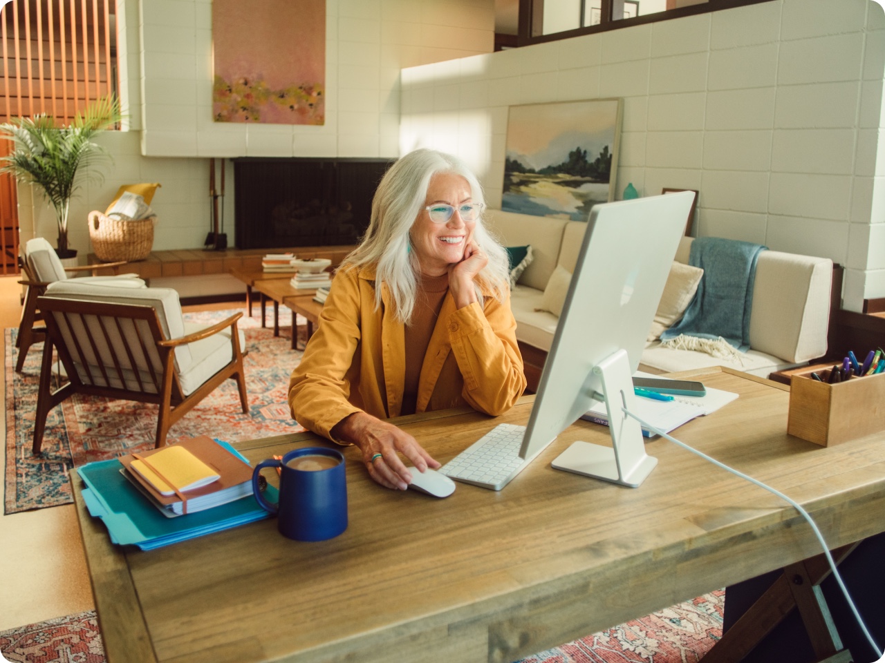 Smiling woman at home on a desktop computer