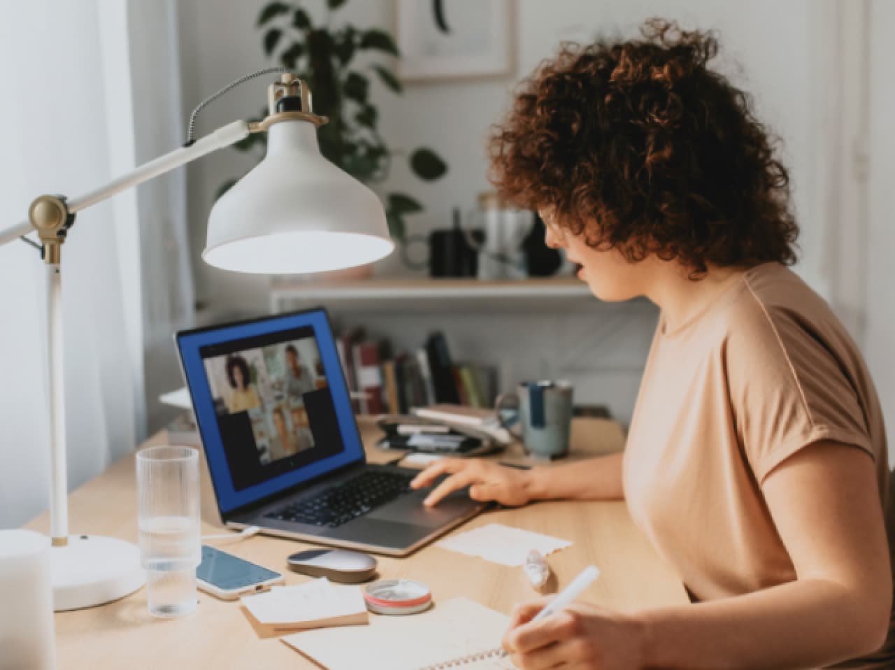 Donna che lavora alla scrivania con fogli e computer portatile