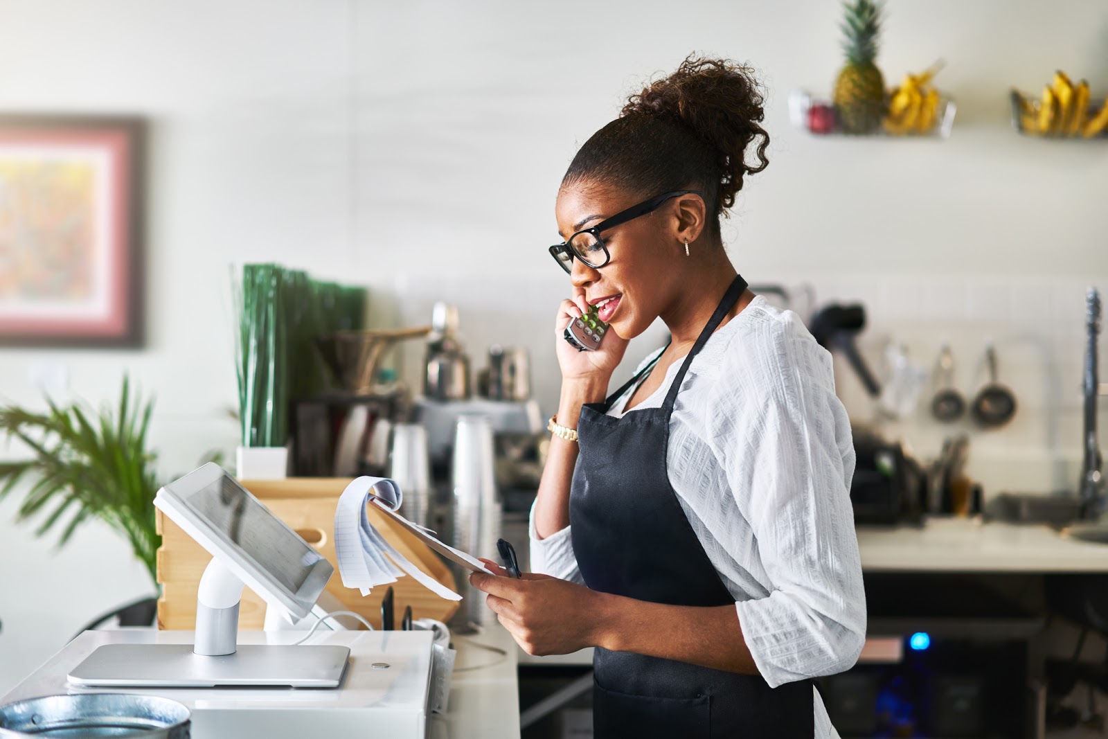 friendly worker taking order on phone at restaurant and writing on notepad during the day