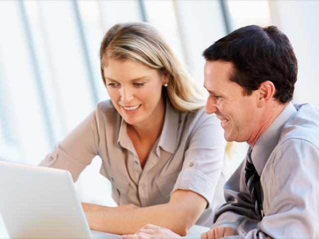 two people smiling at computer