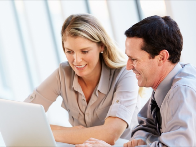 duas pessoas sorrindo para o computador