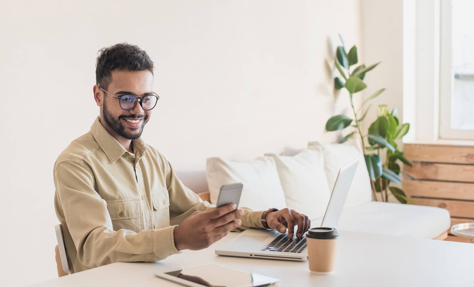Man sitting at desk looking at mobile phone and smiling