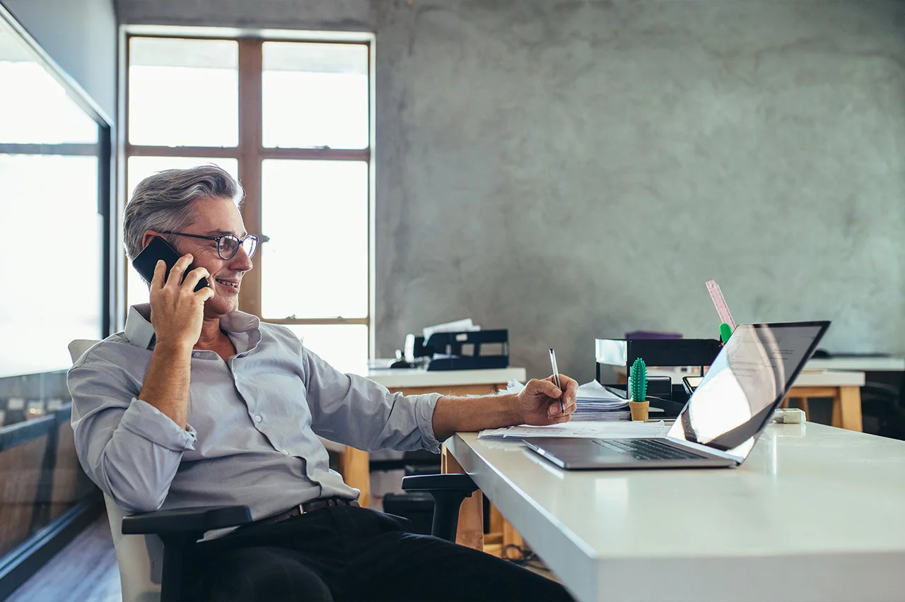 A man wearing a red shirt talks to someone on the phone.