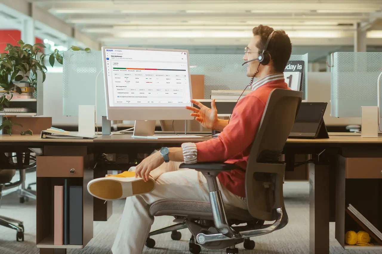 call center agent talking into headset in front of computer screen with a call center dashboard