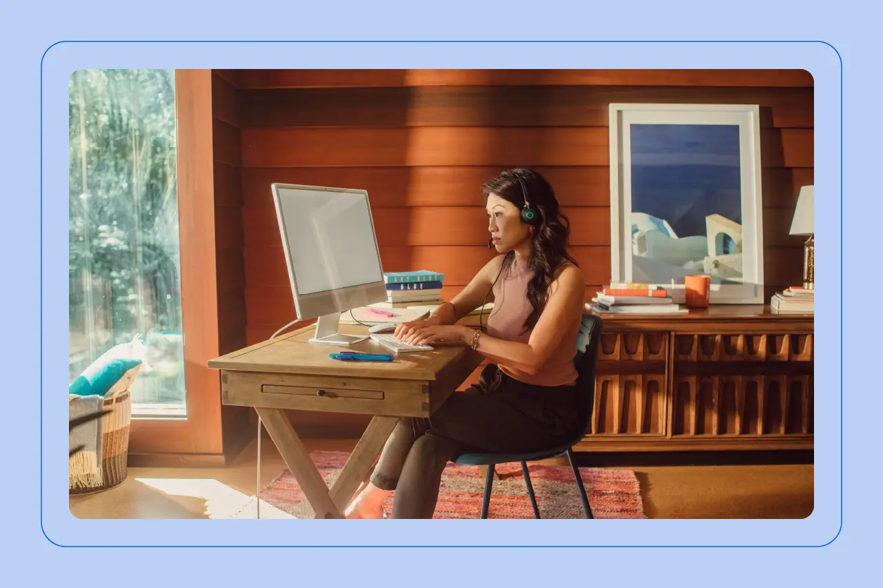 Woman sitting at a desk with headphones on, working on a computer