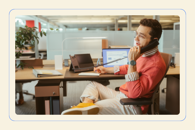 A man wearing a red shirt talks to someone on the phone.