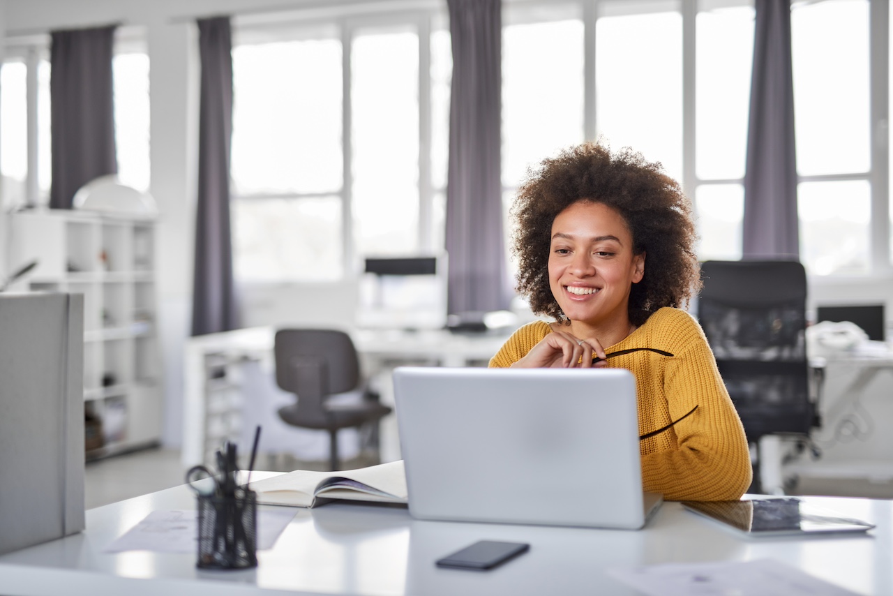 Smiling woman sitting in front of a laptop in an office
