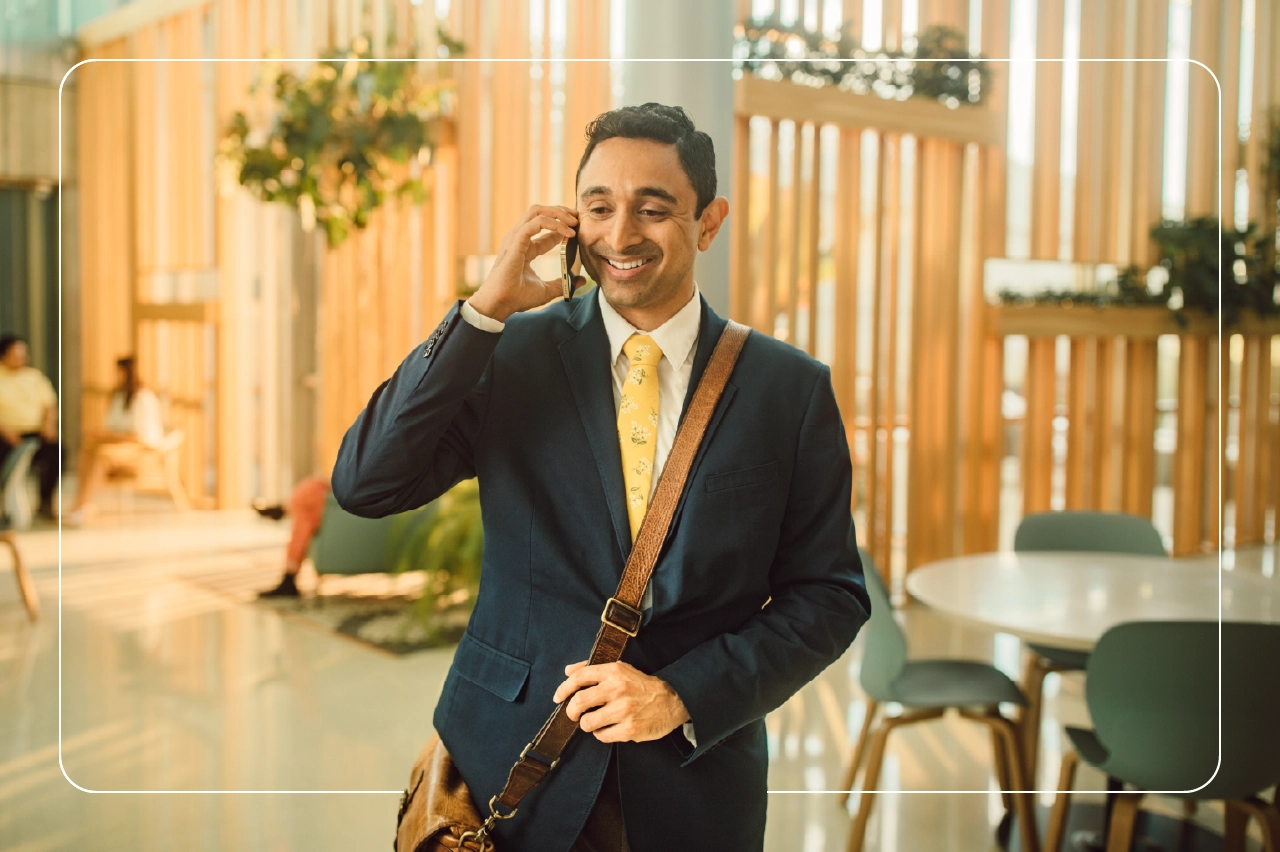 A man wearing a black blazer talks on the phone.