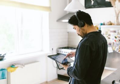 キッチンでヘッドセットを装着してタブレット端末を使用している男性